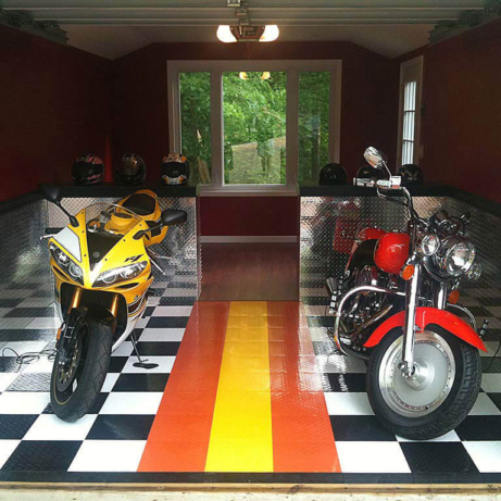 Two motorcycles in a garage with RaceDeck Diamond black, white, orange and yellow tiles.