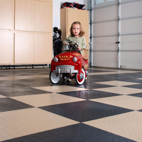 Girl with a toy fire truck in a home garage with RaceDeck XL flooring.