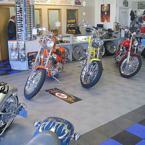 Motorcycles in a display with RaceDeck Diamond alloy, graphite, royal blue and black flooring.