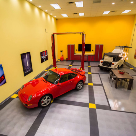 A Porsche and a VW thing in a garage with a lift and CircleTrac garage flooring