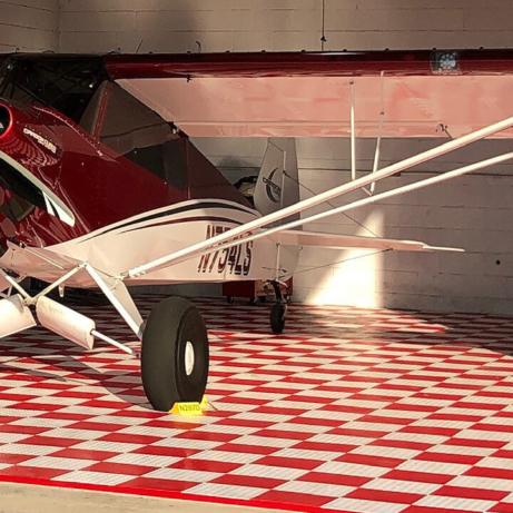 Airplane and motorcycle parked on checkered red and white RaceDeck flooring