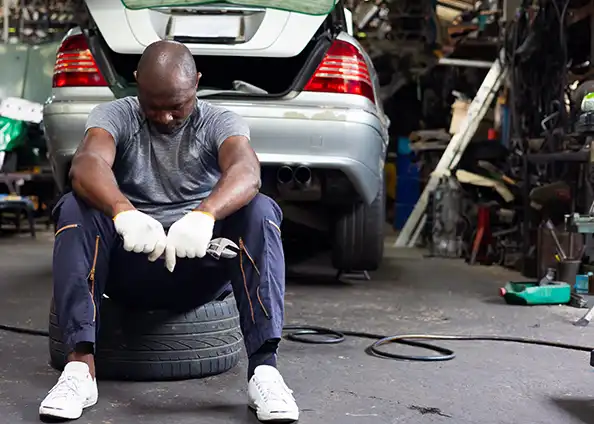 A sad man in his dirt auto shop with low aesthetic value