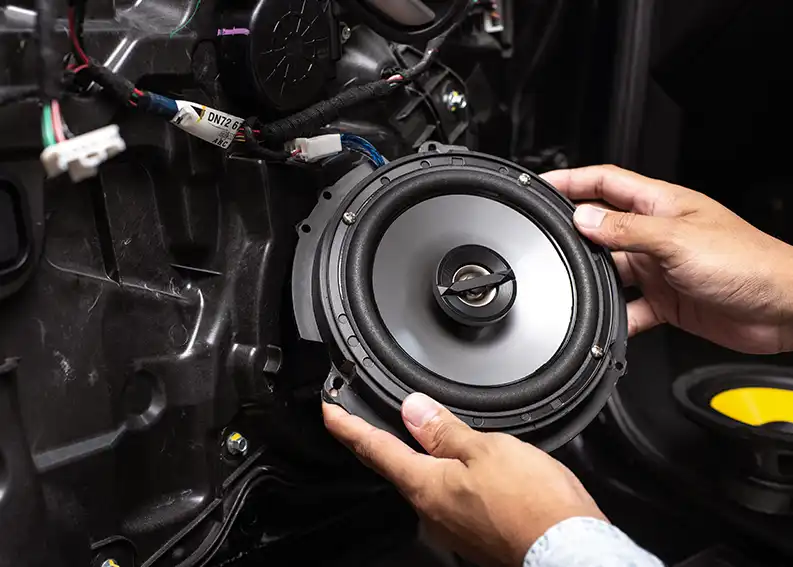 A person installs new speakers in a car.