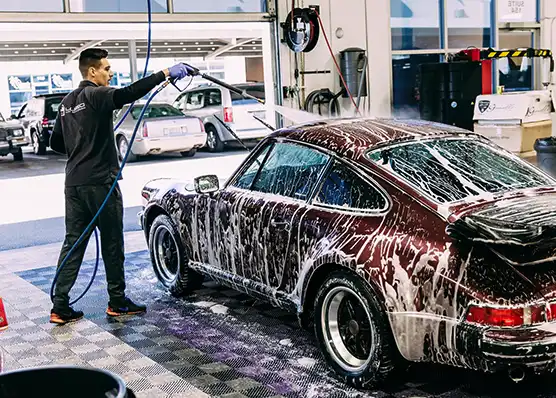 A man washes a Porsche on RaceDeck Free-Flow in a wash bay.