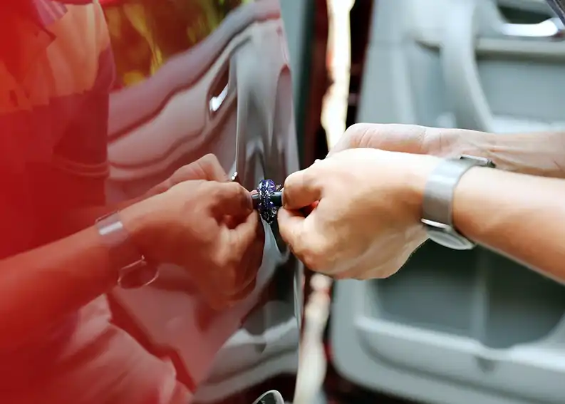 A tech pops a dent a t a paintless body repair shop.