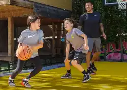 Two young children play basketball with their dad on their SnapSports backyard court.