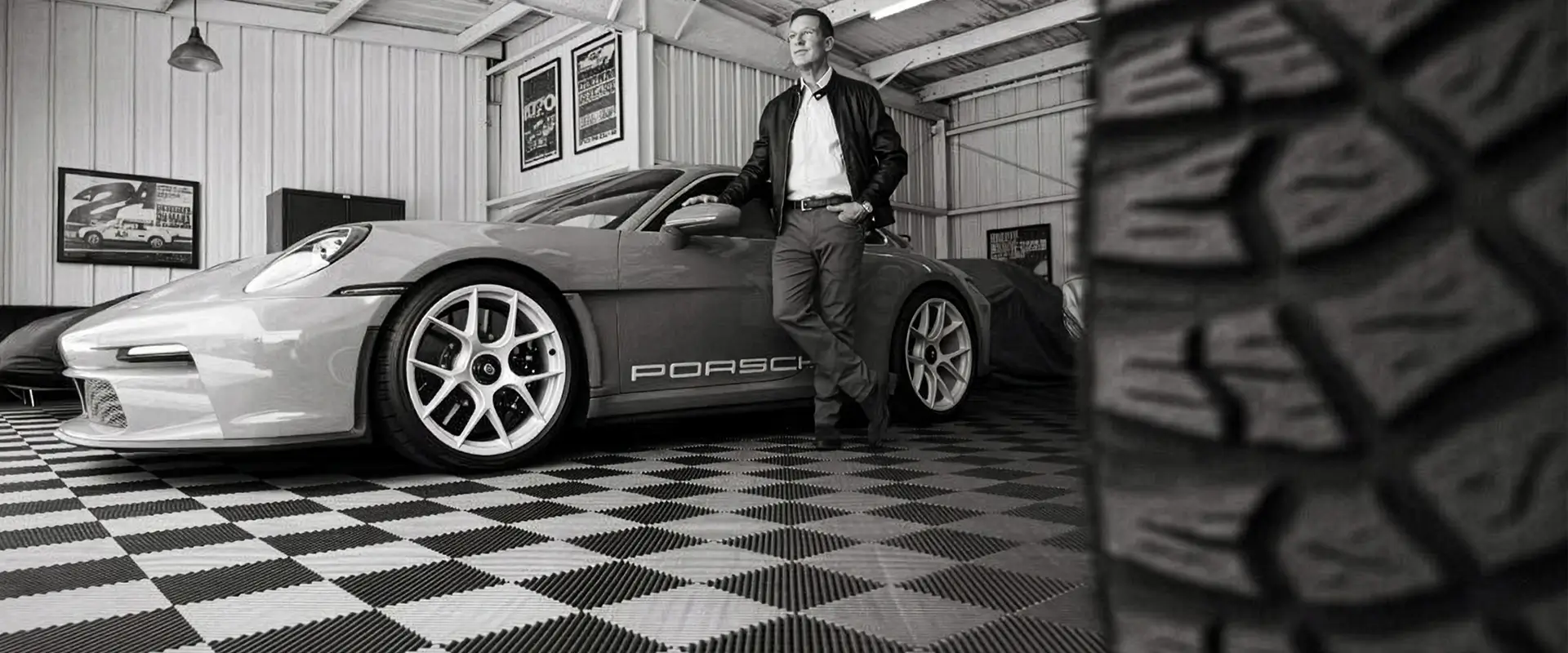 Spike Feresten from Spike's Car Radio in a garage with Free-Flow interlocking tiles. Spike is standing next to a Porche.